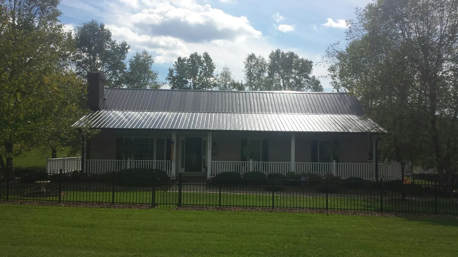 Gray metal roof on a brick ranch with a full width front porch — Gutter Guard Installation work by our crew in Allendale