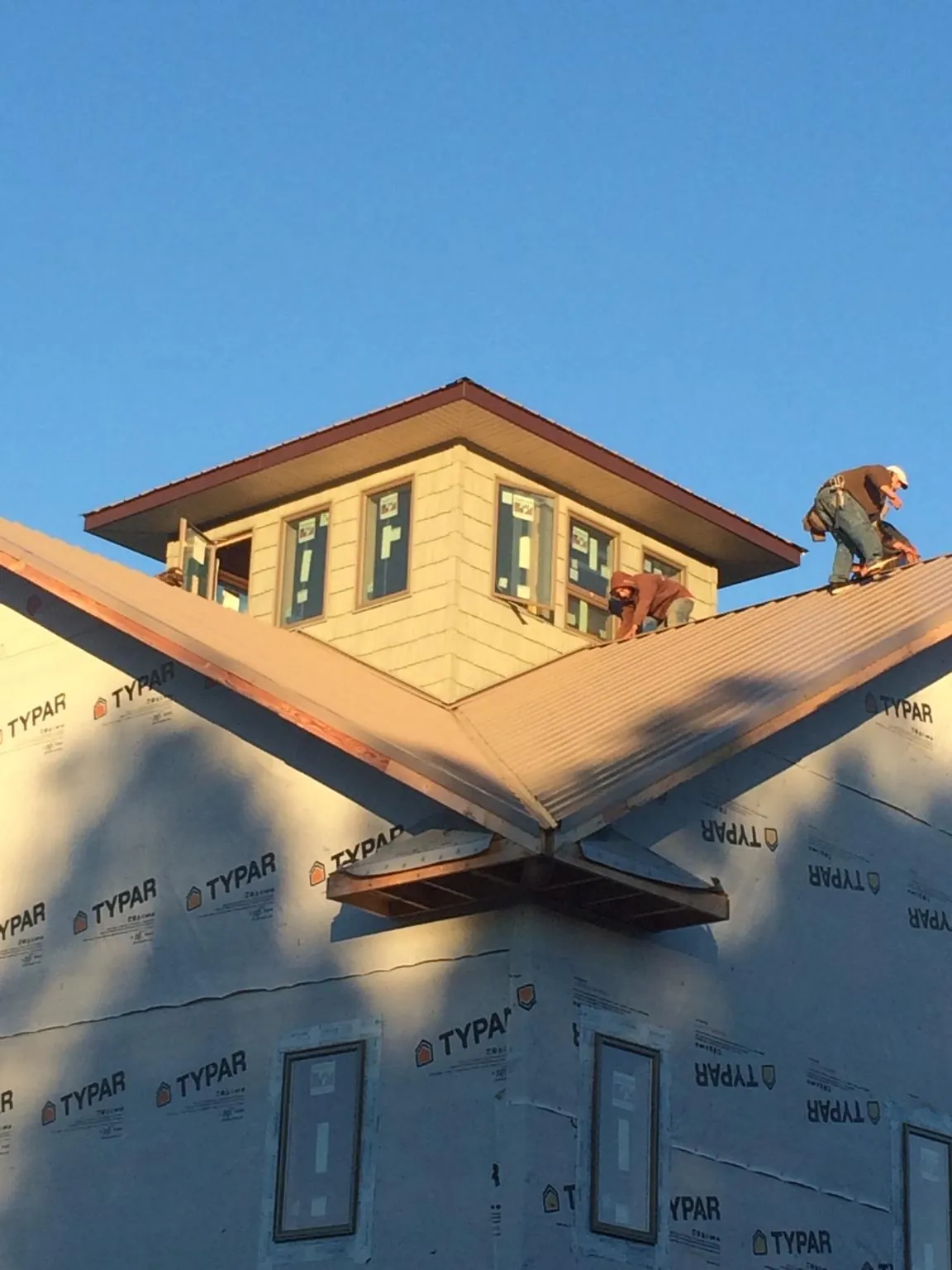 Roofers working around a rooftop cupola on a new metal roof at sunset — Roof Waterproofing in Allendale by Roofing Brothers